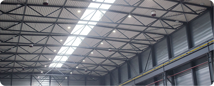 Plafond d’un bâtiment industriel avec structure métallique et éclairage intégré.